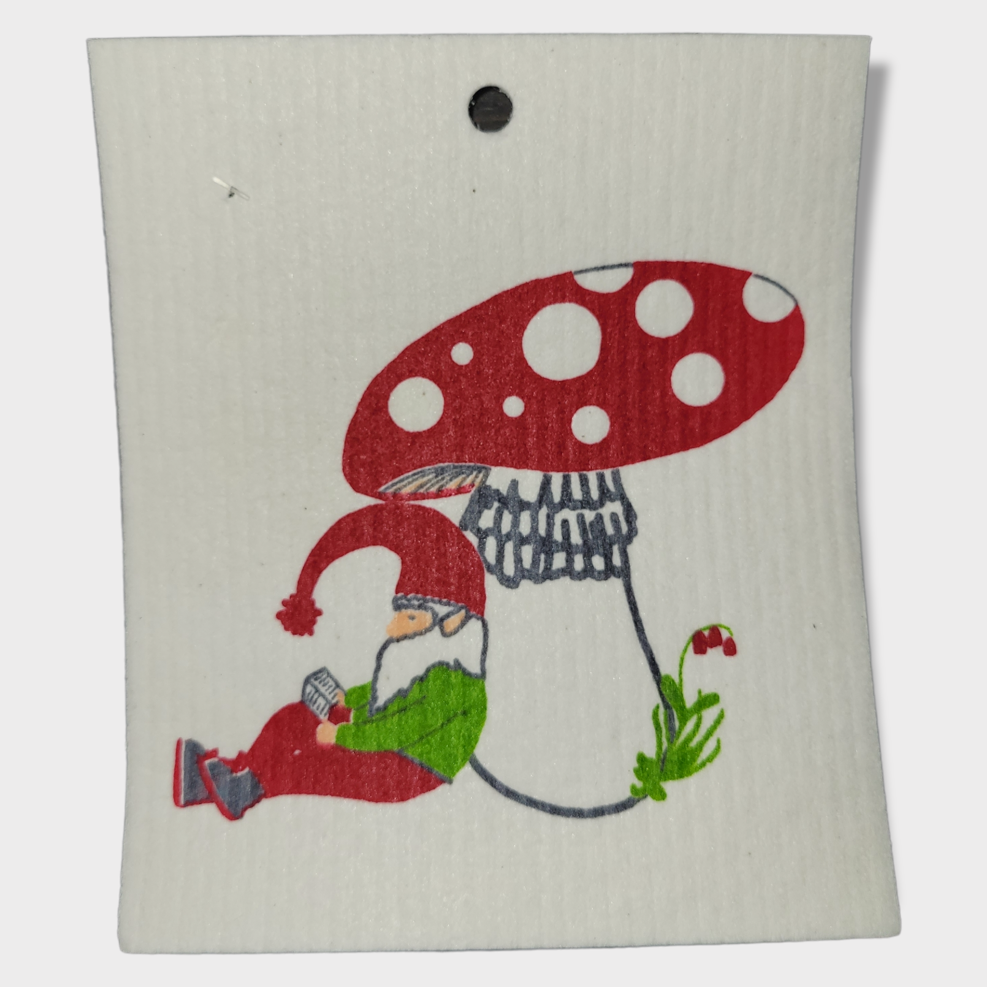 The Dish Cloth: Gnome Leaning on a Mushroom Swedish Dish Cloth features an illustration of a gnome in red clothing resting against a large red and white mushroom on a white background, capturing the charm typical of Swedish dish cloth designs.