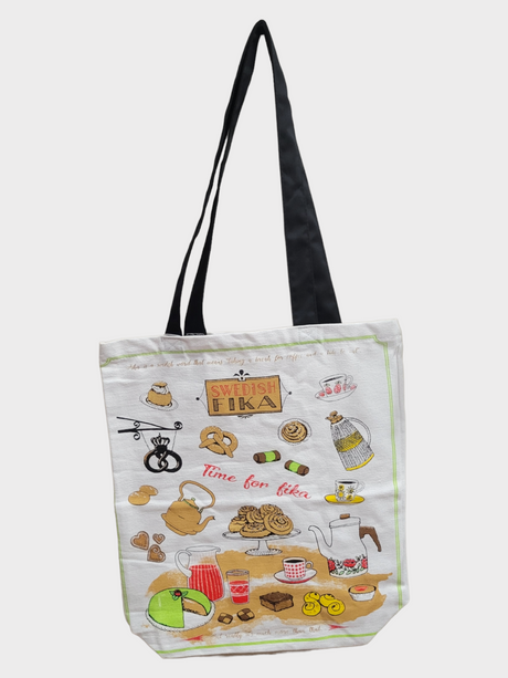 Introducing the Tote: Fika Shopping Tote, a textile bag adorned with whimsical cartoon designs of Swedish fika essentials such as coffee pots, pastries, and cups. The tote features the phrases "Swedish Fika" and "Time for Fika," set against a white background and complemented by black handles.
