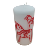 The Red Dala Horse Pillar Candle by Logum Kloster Lys in Denmark features two red Swedish Dala horse motifs with decorative harnesses, adding Scandinavian charm to any space.
