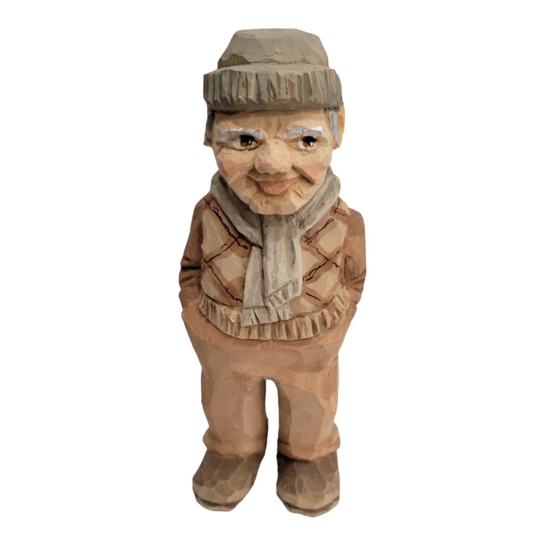 The "Milo" figurine by Bill Erickson is a 6 1/2-inch tall wood-carved figure of an elderly man in a knit hat and scarf, showcasing the artist's skill. He wears a patterned sweater and pants, with his hands resting comfortably in his pockets.