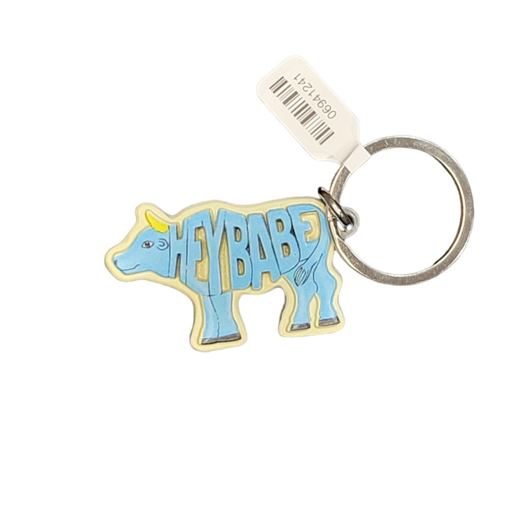 The Keychain: Hey Babe Metal Keyring showcases a delightful cow silhouette emblazoned with the striking HEYBABE design. Made from premium metal, it is securely attached to a robust ring and includes a white tag for convenient identification.