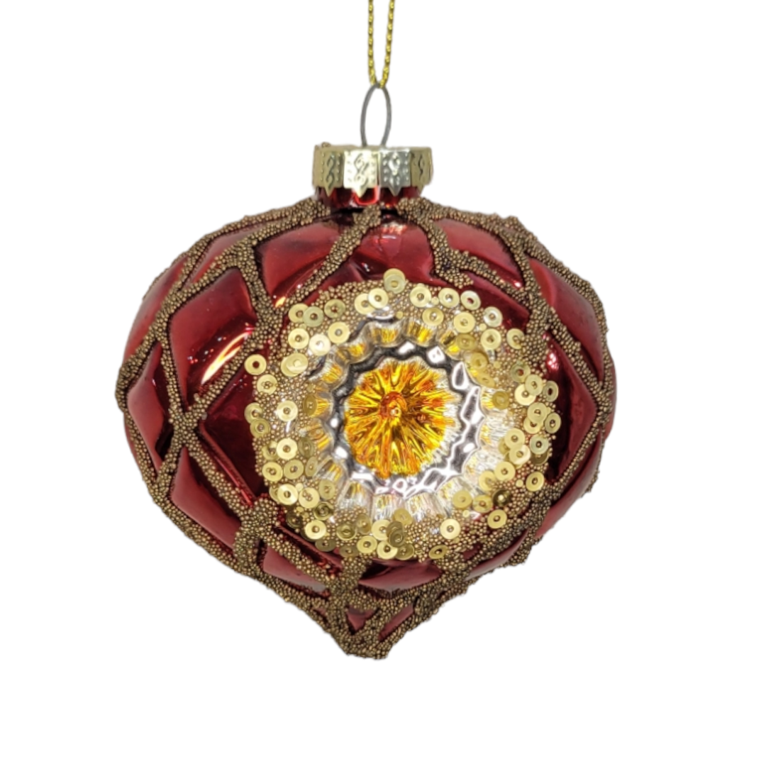 The Ornament: Glass Ball Red Deco showcases a red and gold design with intricate bead and sequin work, highlighted by a central reflective gold pattern, perfectly capturing the timeless elegance of holiday decor.