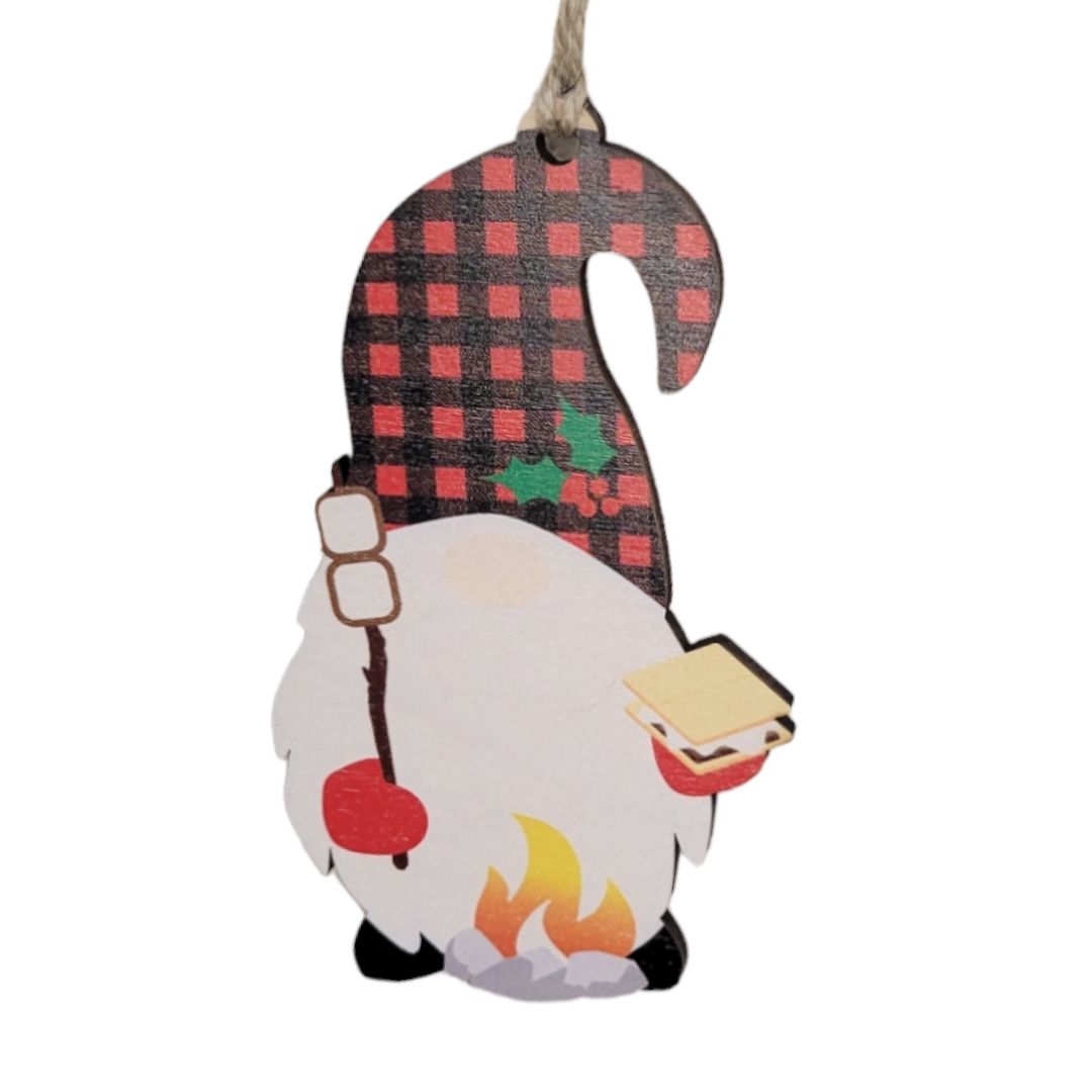 Enhance your camping decor with the charming "Ornament: Camping Gnome - Wood Christmas." This delightful wooden piece showcases a gnome wearing a plaid hat, joyfully holding marshmallows on a stick and a s'more by the campfire—ideal for fans of s'mores-themed ornaments.