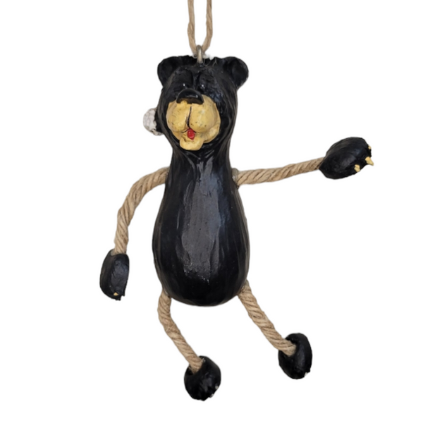 The Ornament: Holiday Bear features a black bear figurine with a yellow face, rope limbs, and a Santa hat, hanging by a rope loop against a white background.