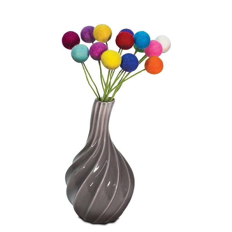 The Flowers: Wool Felted Ball Flower Set includes colorful blossoms with thin green stems, arranged in a gray, twisted ceramic vase.