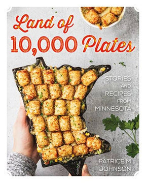 Cover of the book *Land of 10,000 Plates: Stories and Recipes from Minnesota* by Patrice M. Johnson, showcasing a tater tot hotdish arranged in a dish shaped like Minnesota. Parsley garnish and wild rice accompany it, enhancing beloved food traditions.